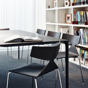 Saya stoel van Arper naast een massief houten tafel