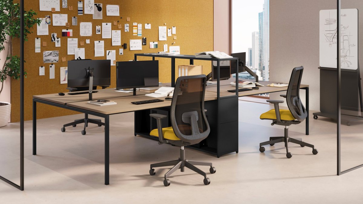 Tegenover elkaar geplaatste werkplekken Sigma van Las Mobili, netstoelen met gele zitting en kurkwand